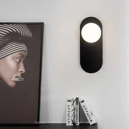 Applique murale ovale minimaliste finition dorée allumée, ambiance cosy chambre