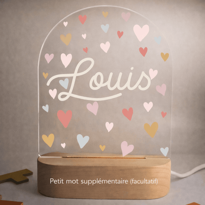 Veilleuse naissance personnalisée cœurs avec prénom gravé posée sur une table de chevet de chambre bébé