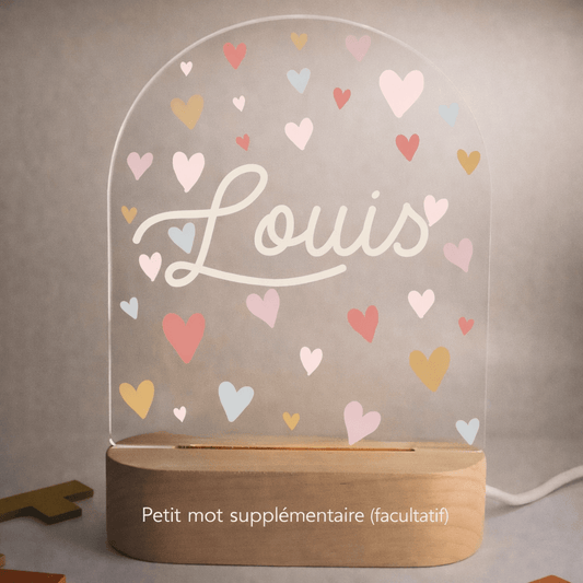 Veilleuse naissance personnalisée cœurs avec prénom gravé posée sur une table de chevet de chambre bébé
